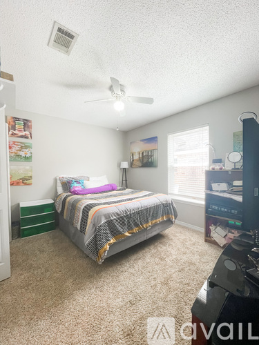 A bedroom with a bed, dresser, and ceiling fan.