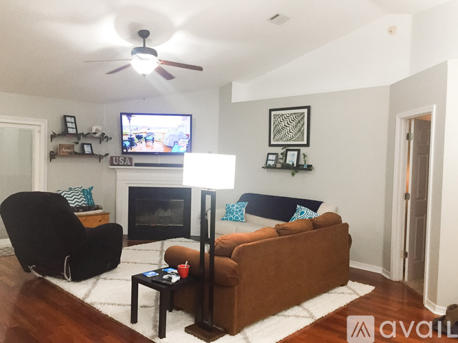 A living room with a black chair, a brown couch, and a fireplace.