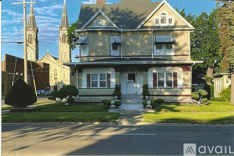A large house with a white door and windows is in front of a church.
