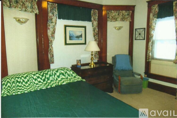 A bedroom with a bed, chair, and lamp.