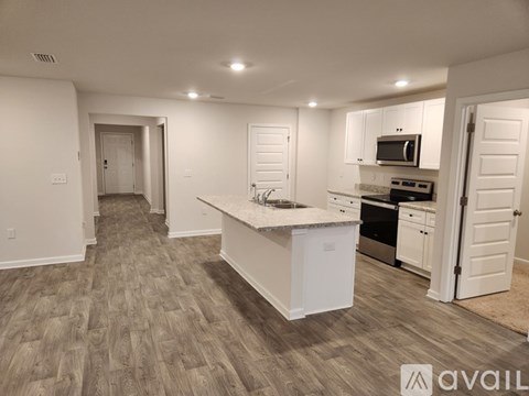 A kitchen with white cabinets and a wooden floor.