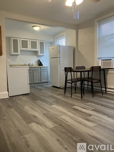 A kitchen with a white refrigerator and wooden flooring.
