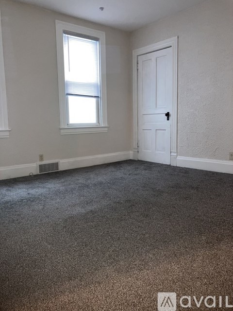 A room with a carpeted floor, a door, and a window.