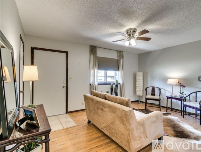 A living room with a beige couch and a ceiling fan.