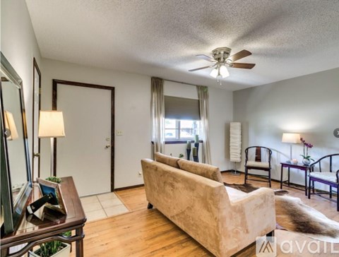 A living room with a beige couch and a ceiling fan.