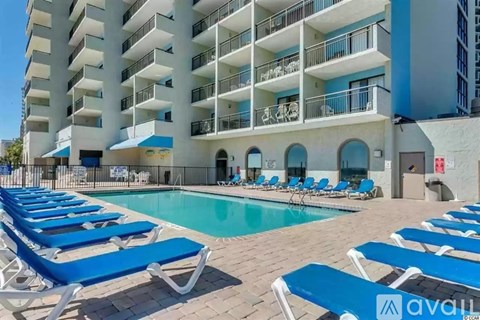 A pool area with sun loungers in front of a white building.
