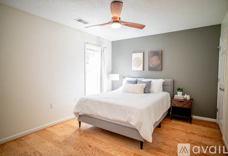 A bedroom with a bed, a ceiling fan, and a nightstand.
