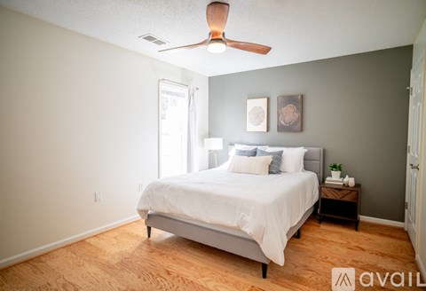 A bedroom with a bed, a ceiling fan, and a nightstand.