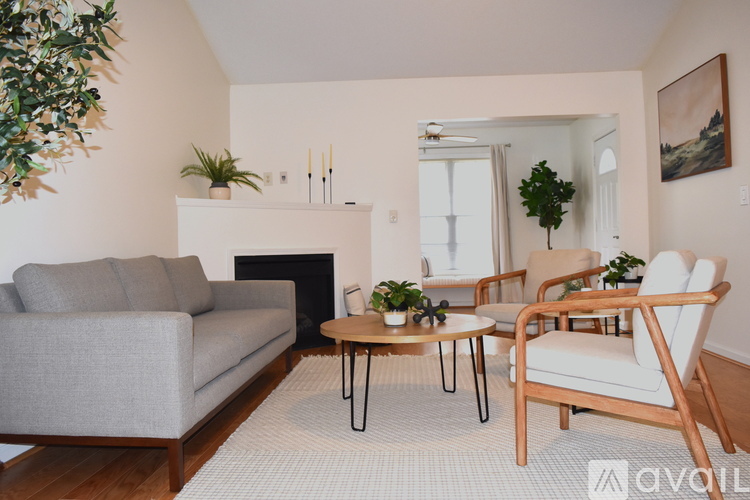 A living room with a grey couch, a wooden chair, and a fireplace.