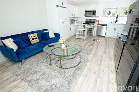 A living room with a blue couch and a glass coffee table.