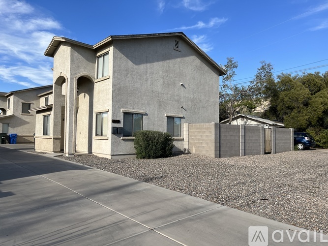 A modern house with a grey exterior and a gravel driveway.