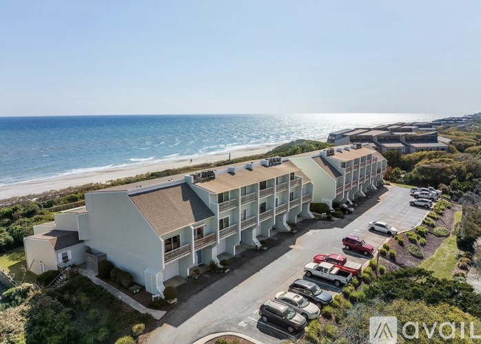 A row of beachfront buildings with cars parked in front.