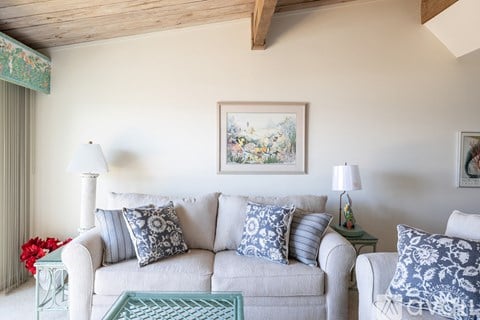 A living room with a white couch and a painting on the wall.