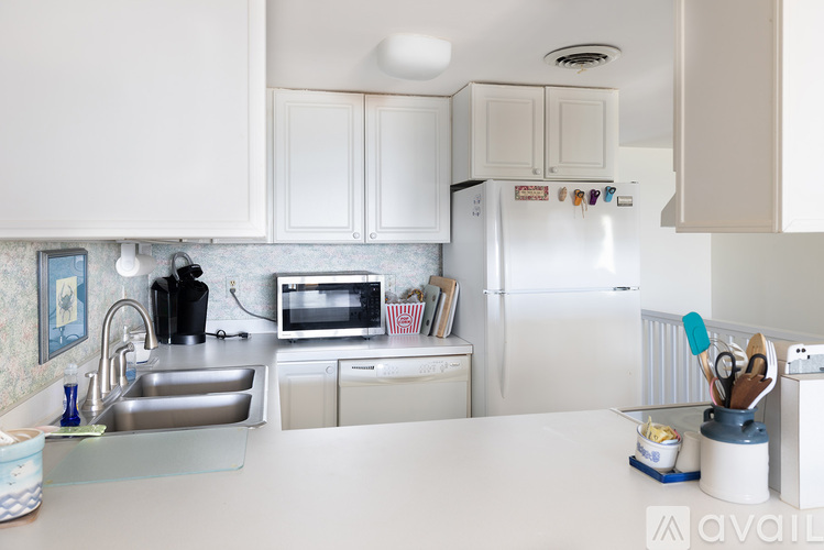 A kitchen with white cabinets and a white fridge.