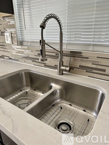 A kitchen sink with a chrome faucet and a marble countertop.