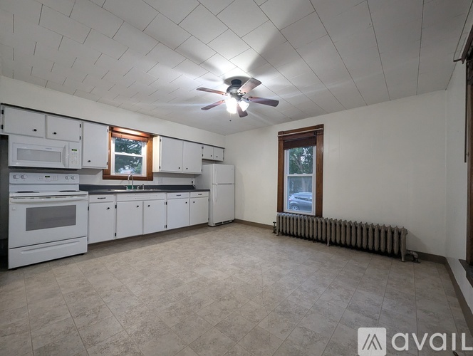 A well-lit kitchen with white appliances and a ceiling fan.