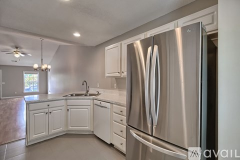 A modern kitchen with a stainless steel refrigerator and white cabinets.
