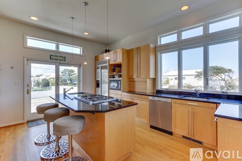A kitchen with wooden cabinets and a large island with a bar stool.