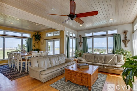 A living room with a ceiling fan and a view of the ocean.
