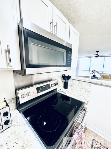 A clean kitchen with a black stove top oven and a black microwave above it.