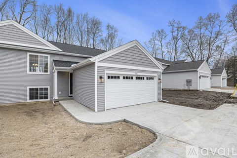A house with a grey siding and a white garage door is for sale.