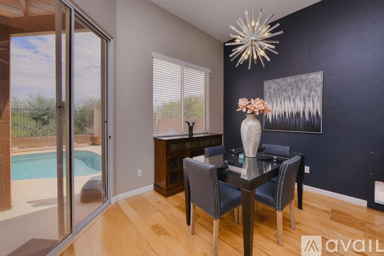 A dining room with a glass table and chairs, a vase with flowers, and a painting on the wall.