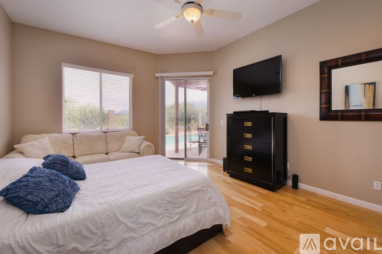 A bedroom with a bed, a television, and a sliding glass door.