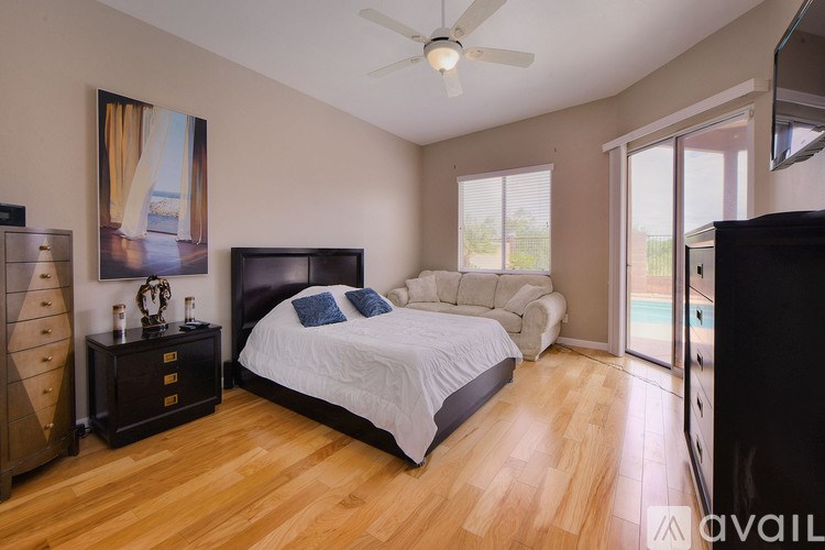 A bedroom with a large bed, a dresser, and a ceiling fan.