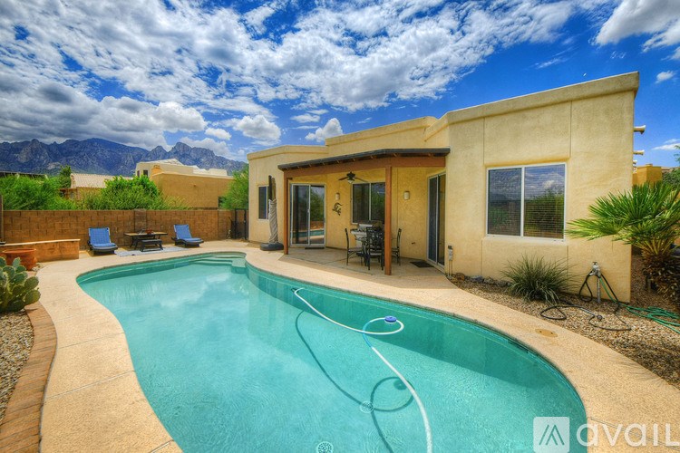 A pool in a backyard with a house and mountains in the background.