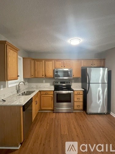 A kitchen with wooden cabinets and a stainless steel refrigerator.