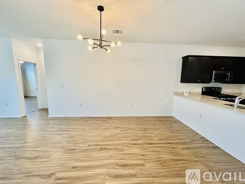 A living room with a wooden floor and a black chandelier.