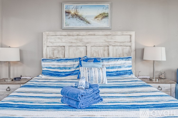A bed with blue and white striped bedding and towels on top.