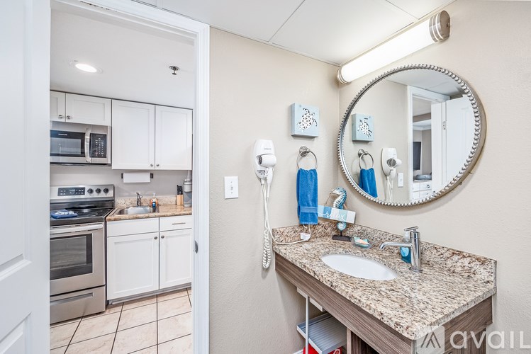 A bathroom with a granite countertop and a round mirror.
