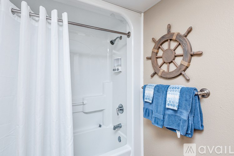 A bathroom with a white tub and a wooden ship's wheel on the wall.