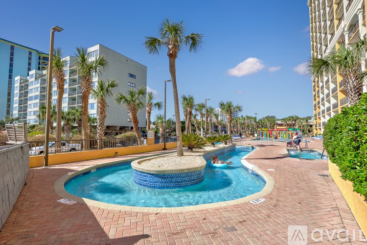 A swimming pool surrounded by palm trees and a building in the background.