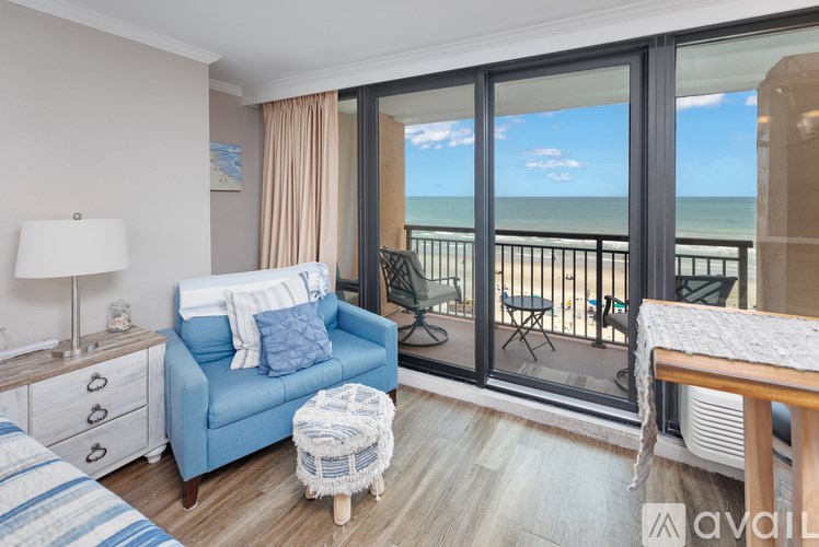 A living room with a blue couch and a view of the ocean through the sliding glass doors.