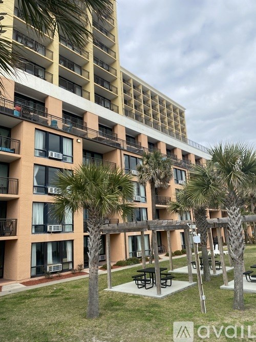 A large apartment complex with balconies and palm trees.