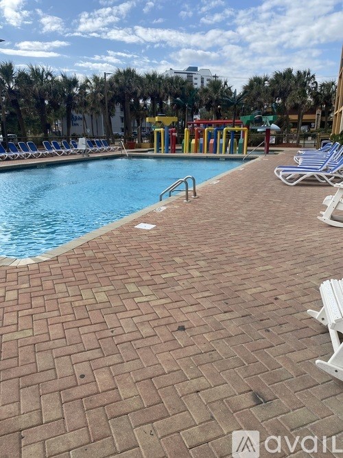 A pool with a brick walkway and lounge chairs.