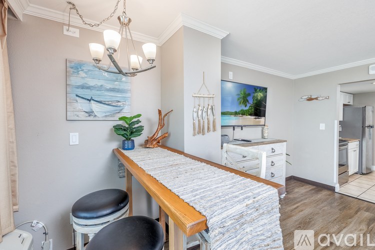 A kitchen with a wooden table and a painting of a beach scene on the wall.