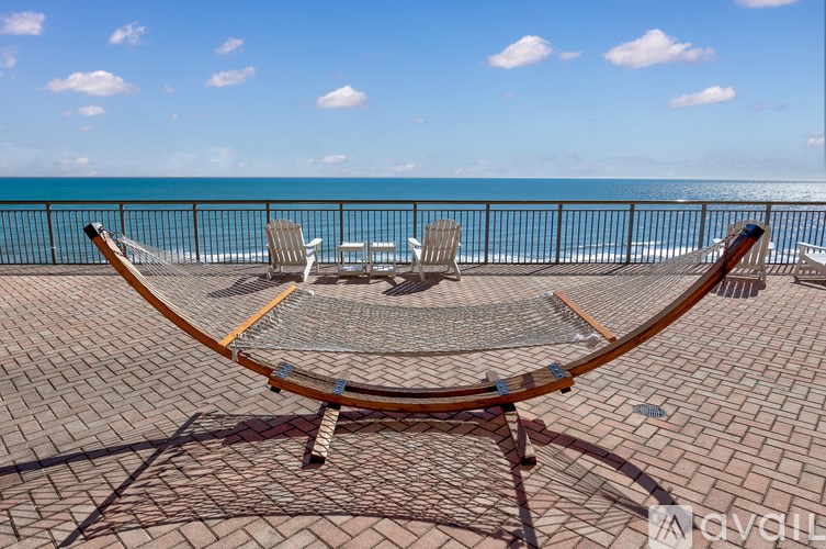 A table and chairs are set up on a patio overlooking the ocean.