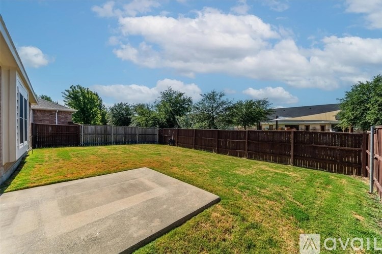 A backyard with a concrete patio and a wooden fence.