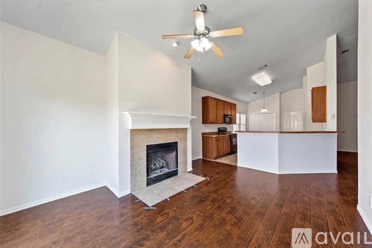 A living room with a fireplace and a ceiling fan.