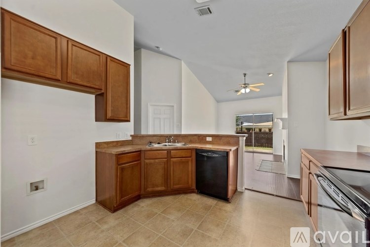 A kitchen with wooden cabinets and a black trash can.