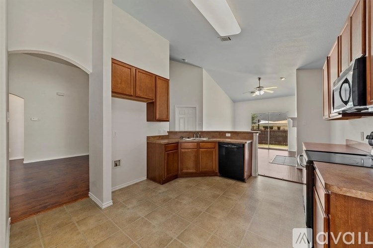 A kitchen with wooden cabinets and a black dishwasher.
