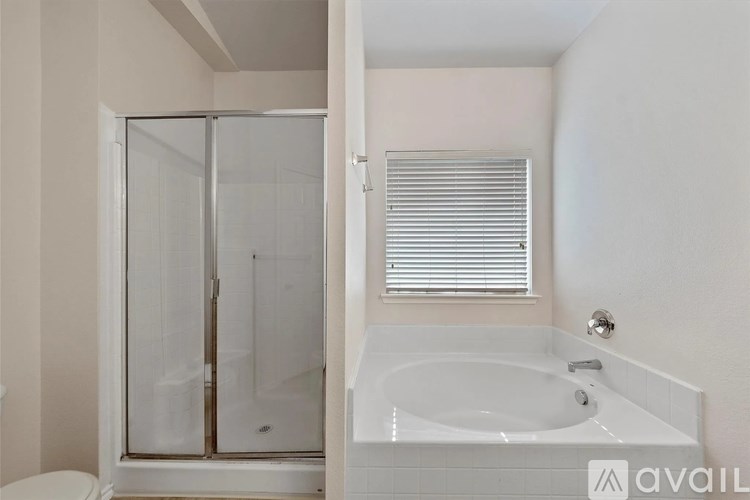 A bathroom with a white tub and a glass shower door.