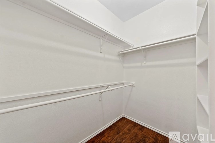 A white wall with a wooden floor and a white shelf.