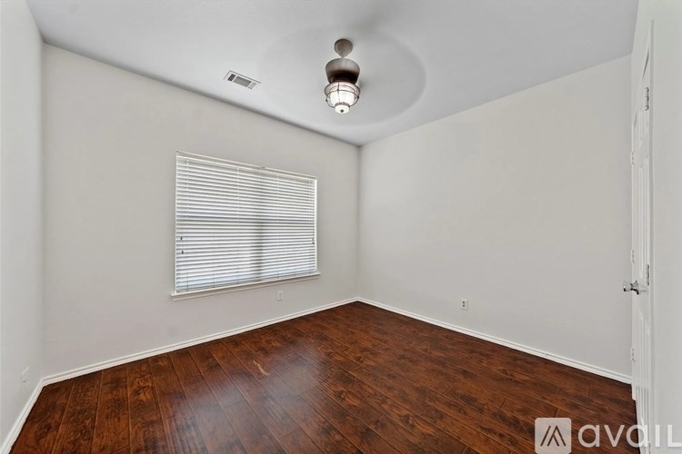 A room with wooden floors and a window with blinds.