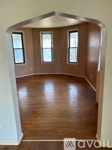 A room with wooden floors and three windows.