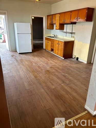 A kitchen with wooden floors and a white fridge.