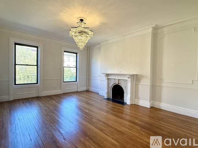 A hallway with wood floors and white walls leading to a door.